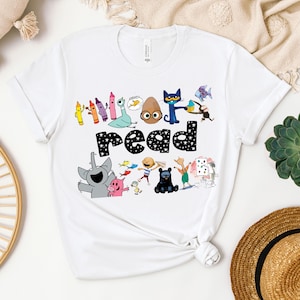 May include: White t-shirt with a colorful graphic of characters from the book "The Book With No Pictures". The graphic includes the text "read" with stars around it.