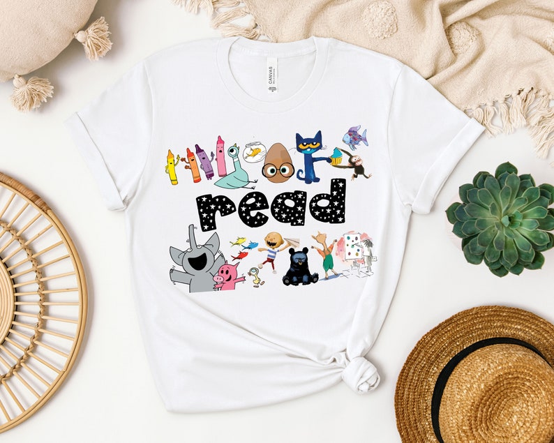May include: White t-shirt with a colorful graphic of characters from the book "The Book With No Pictures". The graphic includes the text "read" with stars around it.
