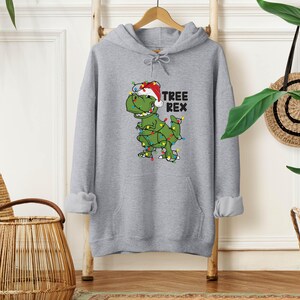 a gray hoodie with a green dinosaur wearing a santa hat