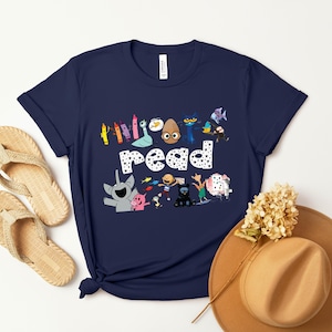 May include: A navy blue t-shirt with a graphic of colorful characters and the words "Everyone read".