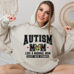 a woman sitting on a bed wearing a hoodie