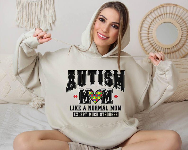 a woman sitting on a bed wearing a hoodie