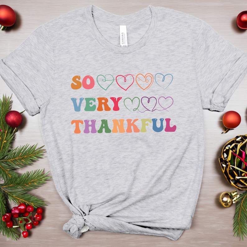 May include: A gray t-shirt with the text "SO VERY THANKFUL" in rainbow colors with hearts between the words.