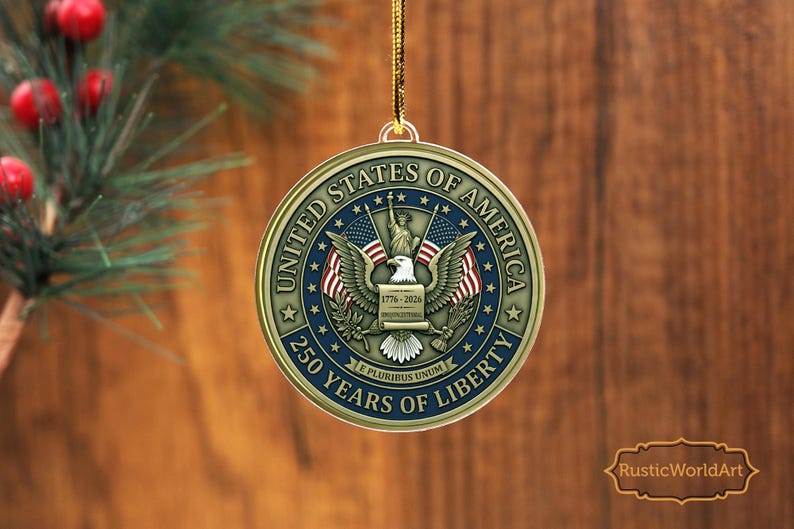 May include: A round, gold-colored Christmas ornament with the text "United States of America" and "250 Years of Liberty." The ornament features an eagle, flags, and the Statue of Liberty. The year range "1776-2026" is also displayed.