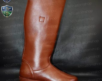 May include: A tall, brown leather riding boot with a low heel. The boot features a smooth, polished finish and a small square detail near the top of the shaft. The boot is designed for equestrian activities.