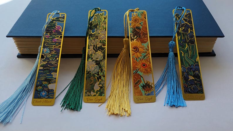 Pu&ograve; includere: Set di cinque segnalibri in metallo dorato con immagini colorate e nappe. I segnalibri presentano opere d'arte di Vincent van Gogh, tra cui "La notte stellata", "Girasoli" e "Iris".
