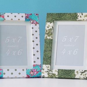 May include: Four decorative picture frames with floral and patterned fabric borders. Each frame has a white interior border and displays the text "5x7" and "4x6". The frames are in various colors, including pink, green, and floral patterns.