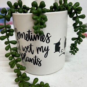 May include: White ceramic mug with black text that reads "Sometimes I wet my plants". The mug is filled with a green succulent plant.