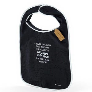 May include: Black baby bib with white edging and the text "I NEVER DREAMED THAT ONE DAY I'D BECOME A GRUMPY OLD MAN BUT HERE I AM, KILLIN' IT." A small brown tag is attached to the bib.