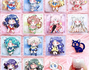 Puede incluir: Una colección de coloridos pines de esmalte con personajes de estilo anime en varias poses y atuendos. Los pines se presentan sobre fondos pastel, mostrando una variedad de diseños, incluyendo un pin de gato negro y un pin de gato blanco.