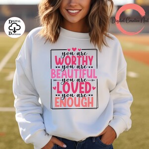 May include: White sweatshirt with a pink graphic that says "You are worthy, you are beautiful, you are loved, you are enough" with pink hearts around the text.