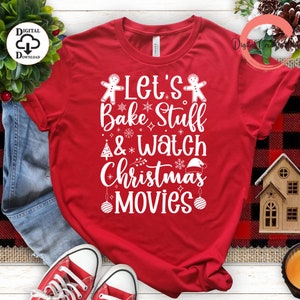 Pode incluir: Camiseta vermelha com texto branco que diz "Let's Bake Stuff & Watch Christmas Movies". O texto é cercado por figuras de pão de gengibre, flocos de neve e enfeites de Natal.