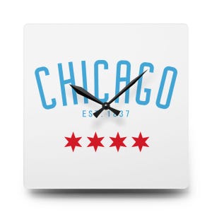 May include: Square white wall clock featuring the word "CHICAGO" in light blue, with "EST. 1837" below. Four red stars are at the bottom. Black clock hands indicate the time. A decorative item for any room.