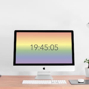 May include: A white iMac desktop computer with a rainbow gradient background on the screen. The time 19:45:05 is displayed on the screen. The computer is on a wooden desk with a white keyboard, a black mouse pad, and a white mouse.