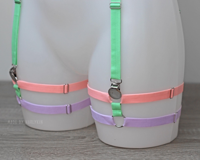 May include: Three adjustable garter belts in pastel colours: light green, pink, and lavender. The garter belts are made of elastic fabric and have metal clasps.