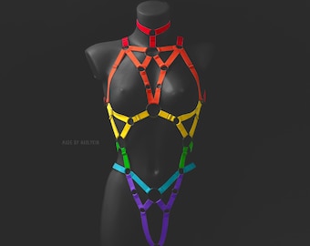 May include: A rainbow-colored body harness with multiple straps and rings. The harness is made of a soft, flexible material and is designed to be worn on the body.
