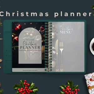 Puede incluir: Un planificador de espiral verde con una cubierta blanca helada. La portada tiene el texto "Your Ultimate Christmas Planner" y la contraportada tiene el texto "Christmas Menu". El planificador está rodeado de decoraciones navideñas, incluyendo bayas rojas, piñas y adornos.