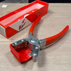 May include: A red and silver nutcracker with red handles and a red base, next to a red and white box with the text "TEXAN-YORK NUT SHELLER". A clear plastic case is also present.