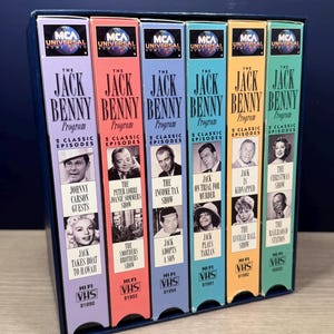 May include: A collection of six VHS tapes of "The Jack Benny Program" in a blue box. Each tape has a different color spine with episode titles and images of the show's stars. The tapes are labeled with the MCA Universal Home Video logo.