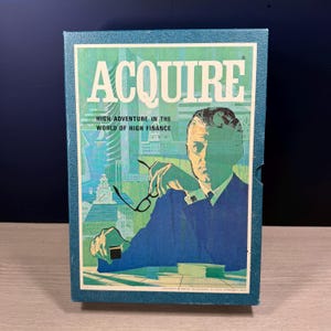 Pode incluir: Uma caixa de jogo de tabuleiro vintage com o título "ACQUIRE" em letras brancas grandes. A caixa apresenta uma ilustração de um homem de terno segurando óculos, com uma paisagem urbana ao fundo. O texto "HIGH ADVENTURE IN THE WORLD OF HIGH FINANCE" também é visível.