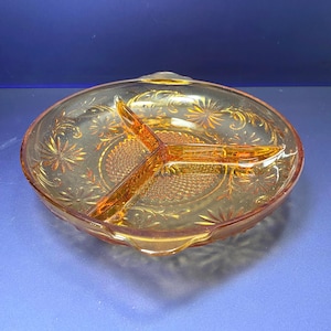 May include: A vintage amber glass divided serving dish with a floral pattern. The dish has three sections and a scalloped edge.