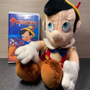 Vintage 1968 Pinocchio Plush Doll 11" Disney Plush Toy and a copy of the 1992 VHS Pinocchio Movie.