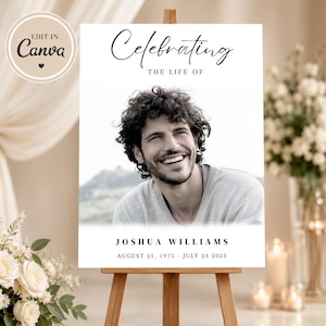 May include: A memorial sign on a wooden easel. The sign reads "Celebrating the Life of" above a black and white photo of a smiling man. Below the photo is "JOSHUA WILLIAMS" and the dates "AUGUST 21, 1975 - JULY 23 2023".