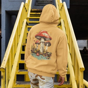 May include: A mustard yellow hoodie with a graphic of red and white mushrooms on the back. The hoodie has a drawstring hood and a kangaroo pocket.