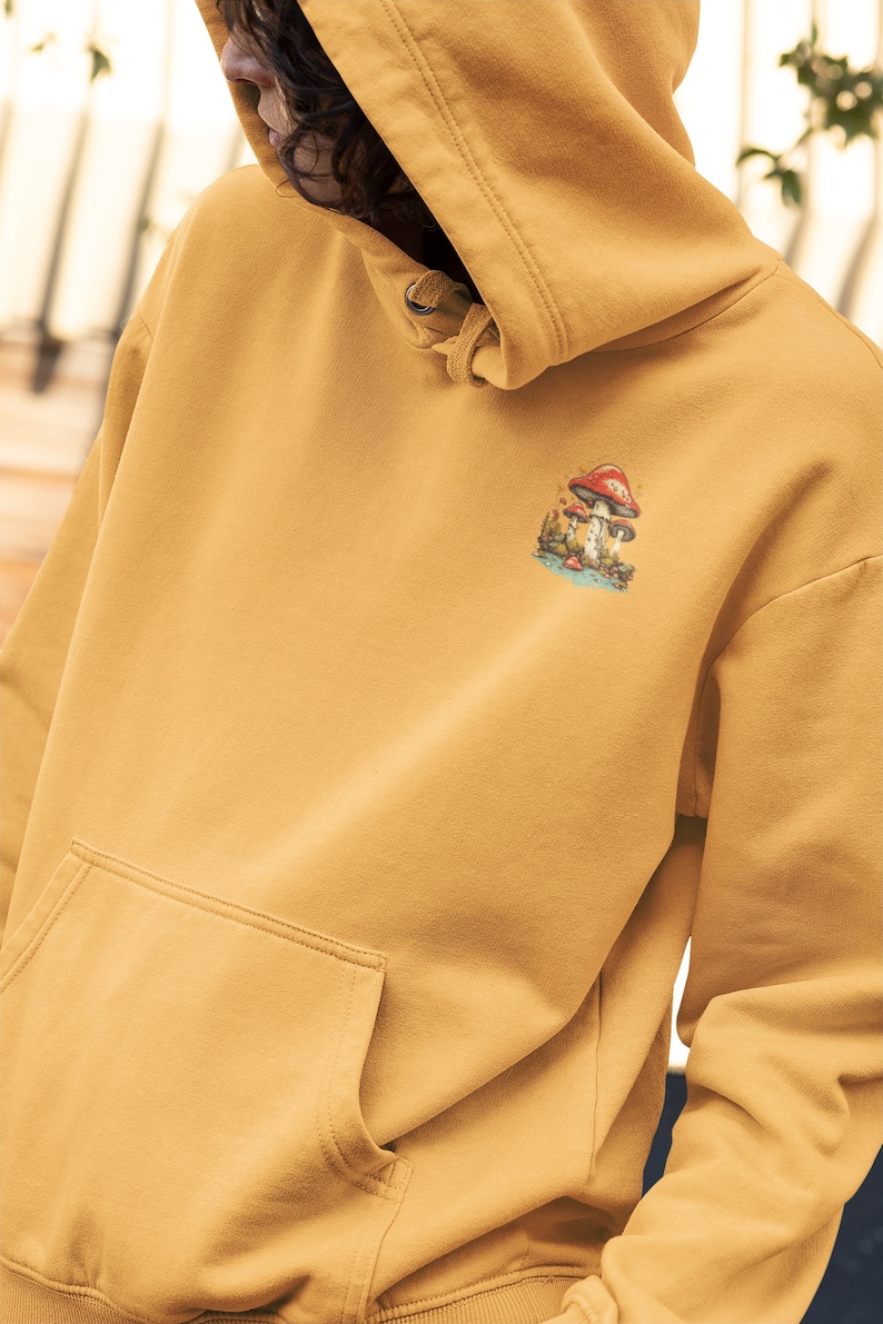 May include: A mustard yellow hoodie with a mushroom graphic on the front. The hoodie has a drawstring hood and a kangaroo pocket.