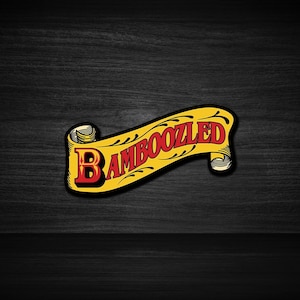 May include: A sticker featuring the word "BAMBOOZLED" in a vintage style. The text is red and yellow, with a black outline. The sticker is set against a black wooden background.