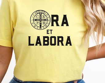 May include: Yellow t-shirt with a black graphic of a Saint Benedict medal and the text "ORA ET LABORA".