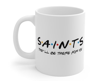 May include: White ceramic coffee mug with a black graphic that says "S.A.I.N.T.S. They'll be there for you".