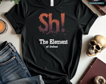 May include: Black t-shirt with the text "Sh! The Element of Defeat" in orange and white. The design features a stylized graphic with a cracked effect. Rolled sleeves and a knot at the bottom. A skull and books are in the background.