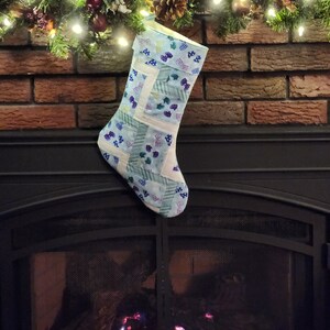 May include: A blue and white patchwork Christmas stocking hangs above a fireplace with a roaring fire.