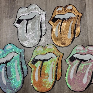 May include: Five sequined patches shaped like lips with tongues sticking out. The top row features silver and gold colors. The bottom row includes teal, iridescent orange-yellow, and light pink colors. Each patch has white teeth and black accents.