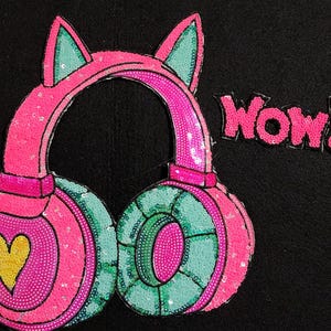 May include: Pink and green sequined headphones with cat ears and the word "WOW!" in pink sequins.