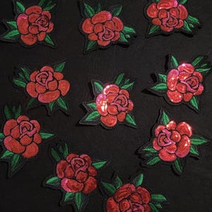 May include: Ten red sequin rose patches with green leaves. The roses are embroidered with sequins and have a vintage look.