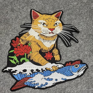 Peut inclure: Un patch brodé représentant un chat de dessin animé chevauchant un poisson sur une vague. Le chat est orange et blanc avec un nez rouge et des moustaches noires. Le poisson est bleu et blanc avec une nageoire rouge. La vague est blanche avec des accents bleus et noirs.