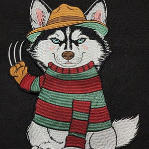 May include: An embroidered patch featuring a husky dog wearing a brown fedora and a red and green striped sweater. The husky has light blue eyes, pink cheeks, and a paw raised with three silver-colored metal claws extending from the fingers.