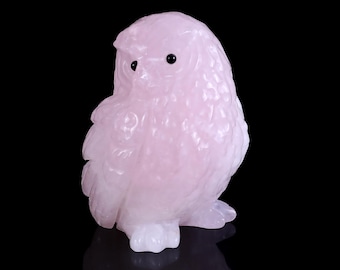 May include: A pink carved owl figurine made of rose quartz with black eyes.