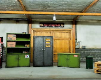Puede incluir: Un modelo en miniatura de un taller de garaje con una máquina expendedora de Coca-Cola, armarios metálicos verdes, un armario metálico negro, una paleta de madera y un cubo de basura verde.