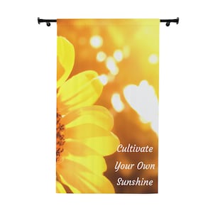 Può includere: Una bandiera da giardino decorativa con un primo piano di un girasole giallo brillante su uno sfondo solare sfocato. La bandiera presenta il testo "Cultivate Your Own Sunshine" in bianco, con un carattere elegante.
