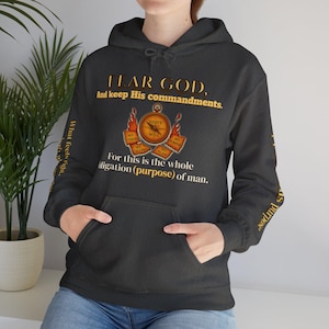 May include: Dark grey hooded sweatshirt with a front pocket. The gold text on the front reads "FEAR GOD, And keep His commandments." A compass graphic is in the center, with additional text. The sleeve has text that reads "As purpose."