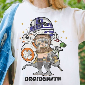 May include: White t-shirt featuring a cartoon illustration of Star Wars characters R2-D2, BB-8, and a droid with the text "DROIDSMITH".