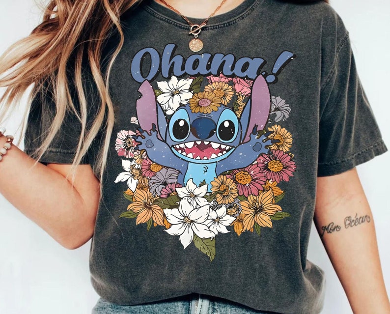 May include: A dark gray t-shirt with a blue Stitch character from Lilo & Stitch surrounded by colorful flowers. The text "Ohana!" is printed above Stitch.