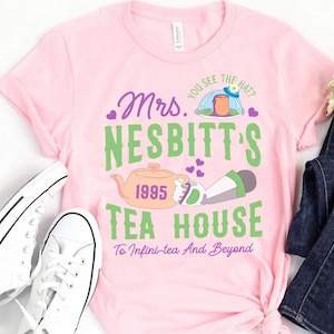 K&ouml;nnte beinhalten: Pinkes T-Shirt mit einem gr&uuml;nen und violetten Grafikdesign mit einer Teekanne, einer Comicfigur und dem Text "Mrs. Nesbitt's Tea House 1995 To Infini-tea And Beyond".