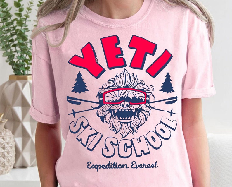 Puede incluir: Camiseta rosa con un gr&aacute;fico de un Yeti con gafas y el texto "YETI SKI SCHOOL Expedition Everest".