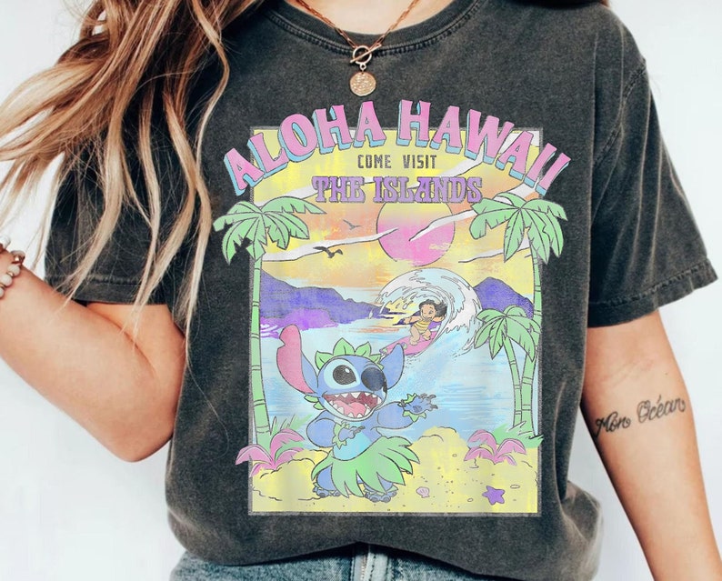 May include: Black t-shirt with a graphic print of Stitch from Lilo & Stitch. The graphic features Stitch in a hula skirt with a sunset and palm trees in the background. The text "Aloha Hawaii Come Visit The Islands" is printed above the graphic.