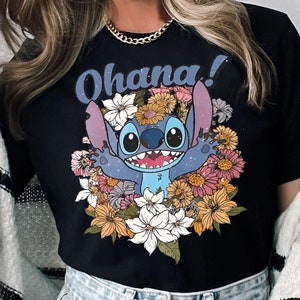 May include: Black t-shirt with a blue Stitch character from Lilo & Stitch surrounded by colorful flowers. The text "Ohana!" is printed above the character.