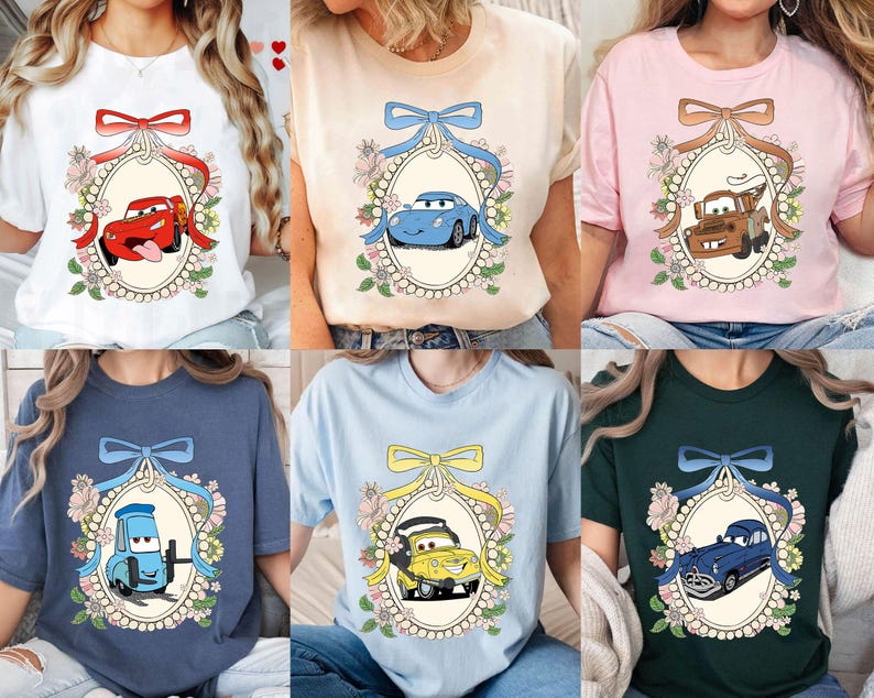 Op de afbeelding: Zes verschillende T-shirts met een cartoonauto in een parelmoerachtig frame met bloemmotieven. De auto's zijn rood, blauw, geel en bruin. De shirts zijn wit, roze, lichtblauw, donkerblauw en groen.